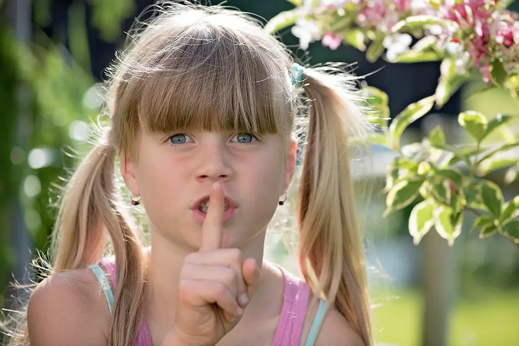 Kleines Mädchen zeigt mit ihrem Finger Pssst