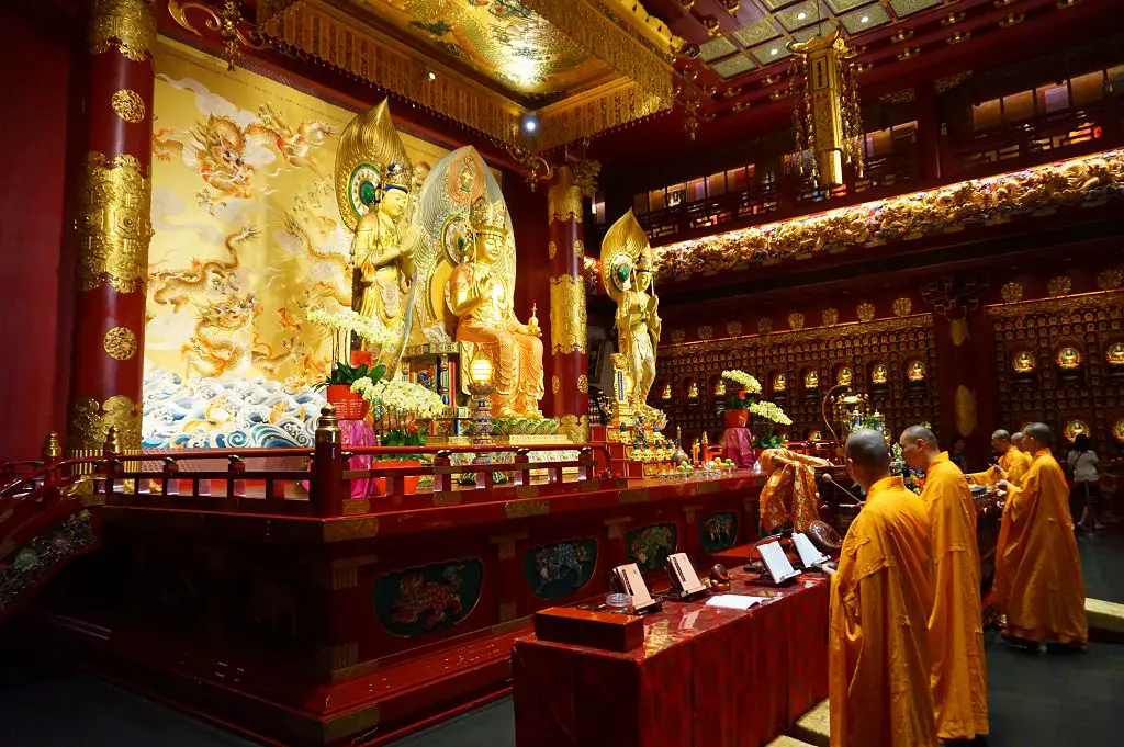 Innenbereich vom Buddha Tooth Relic Tempel mit beteneden Mönchen