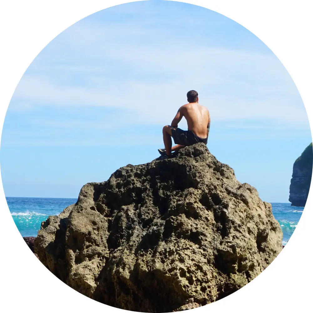 Marco sitzt auf einem Felsen und schaut aufs Meer